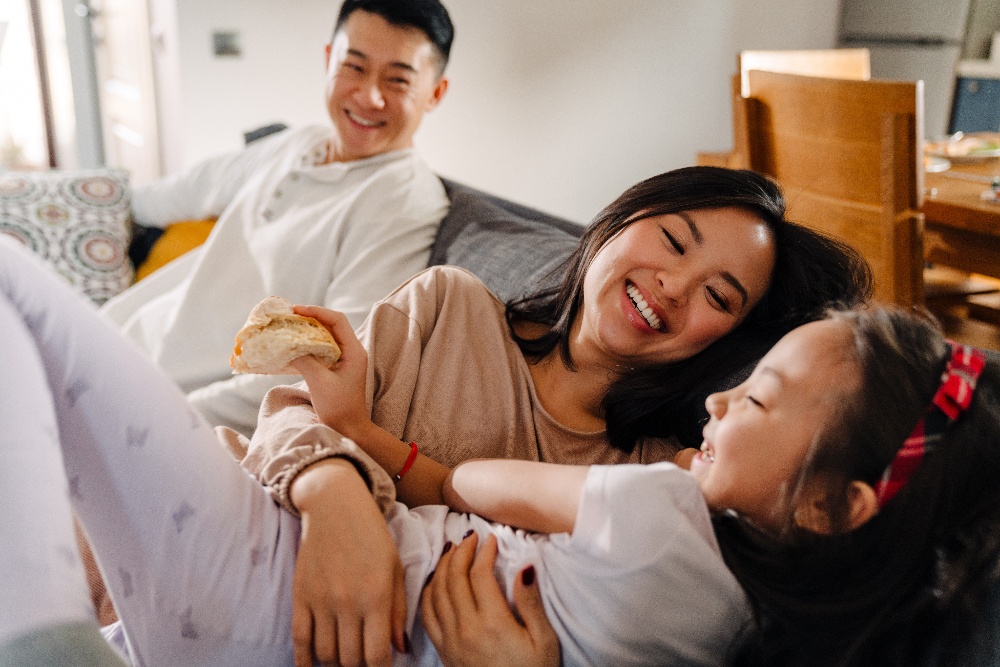 Family playing on couch together in their home.