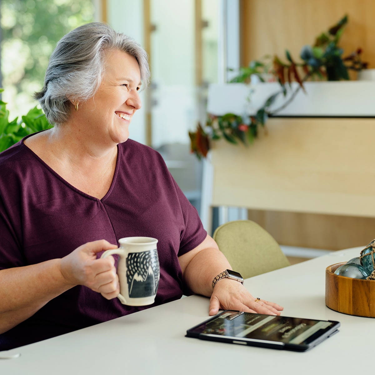 Woman holding a coffee mug and looking at her iPad