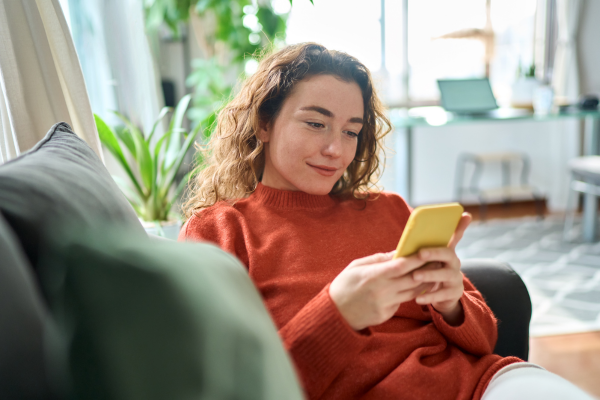 young women lounging on couch smiling at phone